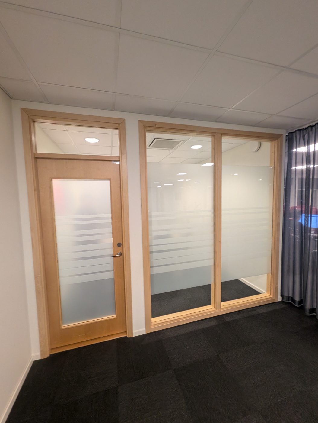Kontorsdörr och glasvägg med frostad dekorfilm i ränder som begränsar insyn