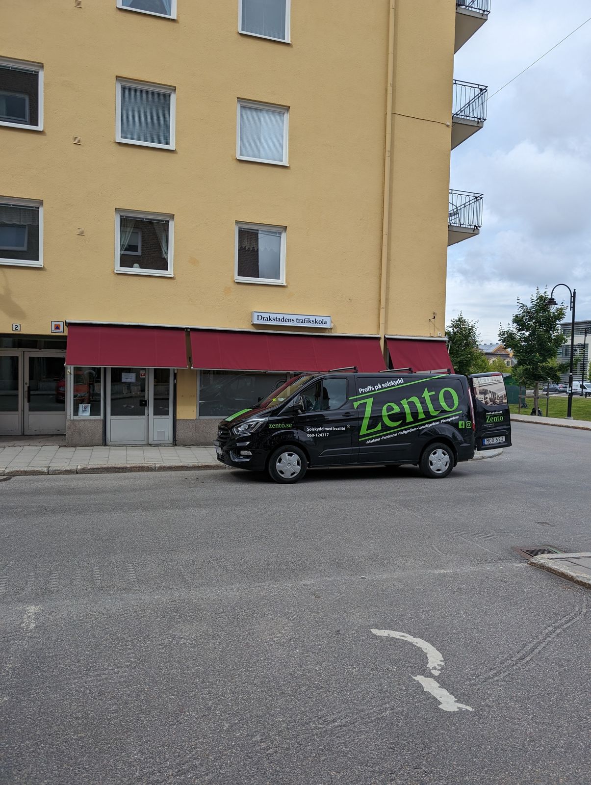 Röda markiser över butiksfönster med Zentos svarta bil parkerad framför