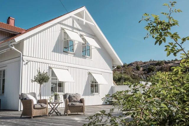 Fönstermarkiser på vit villa med altan