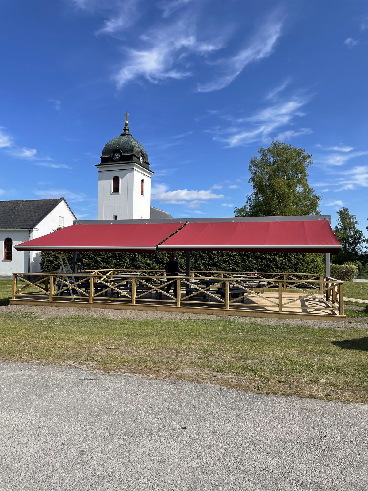 Lång röd markis över en uteservering med trästaket